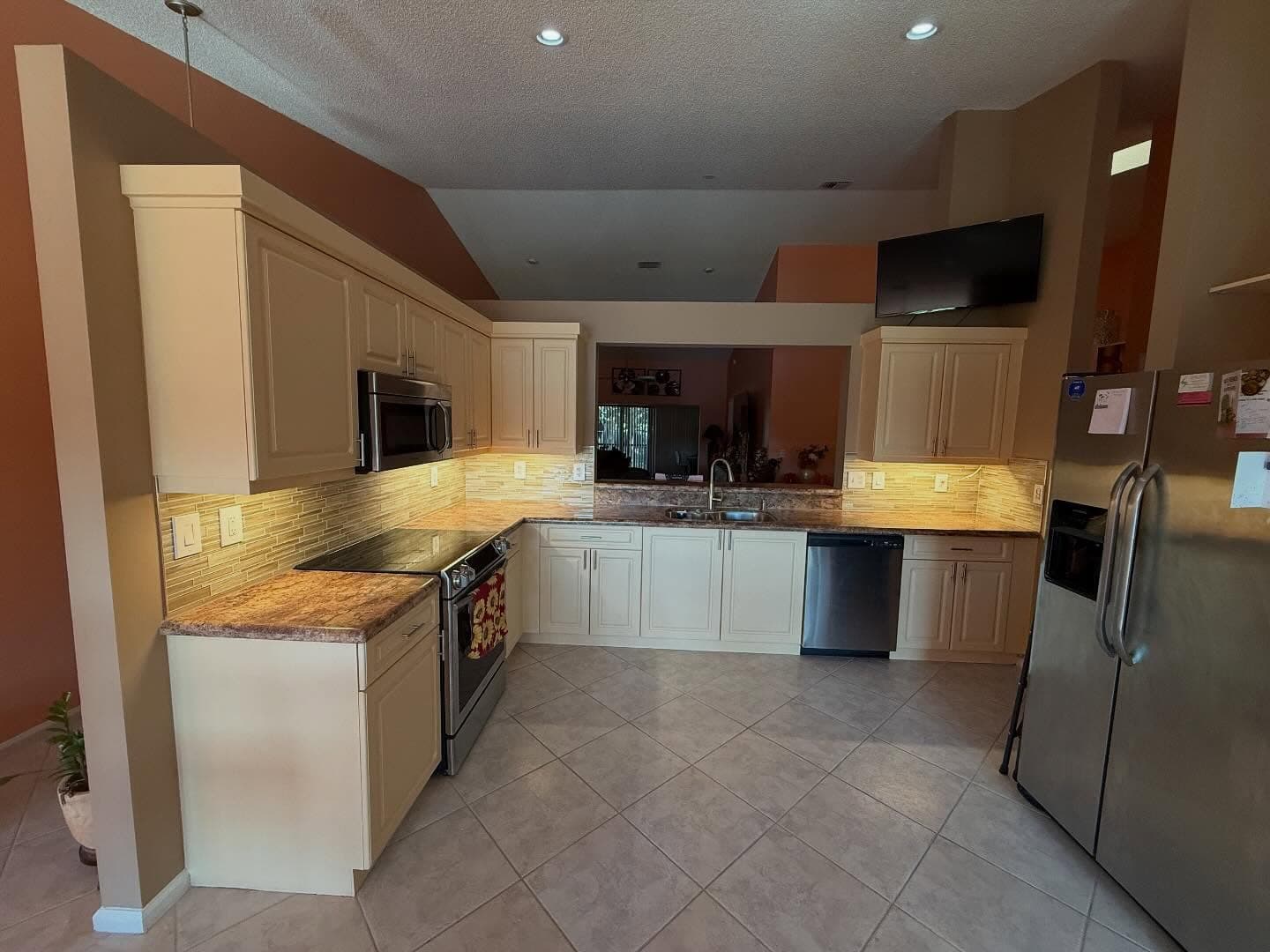 Kitchen makeover by I&I Home Repair, after: cream painted cabinets, new tile backsplash, and neutral walls
