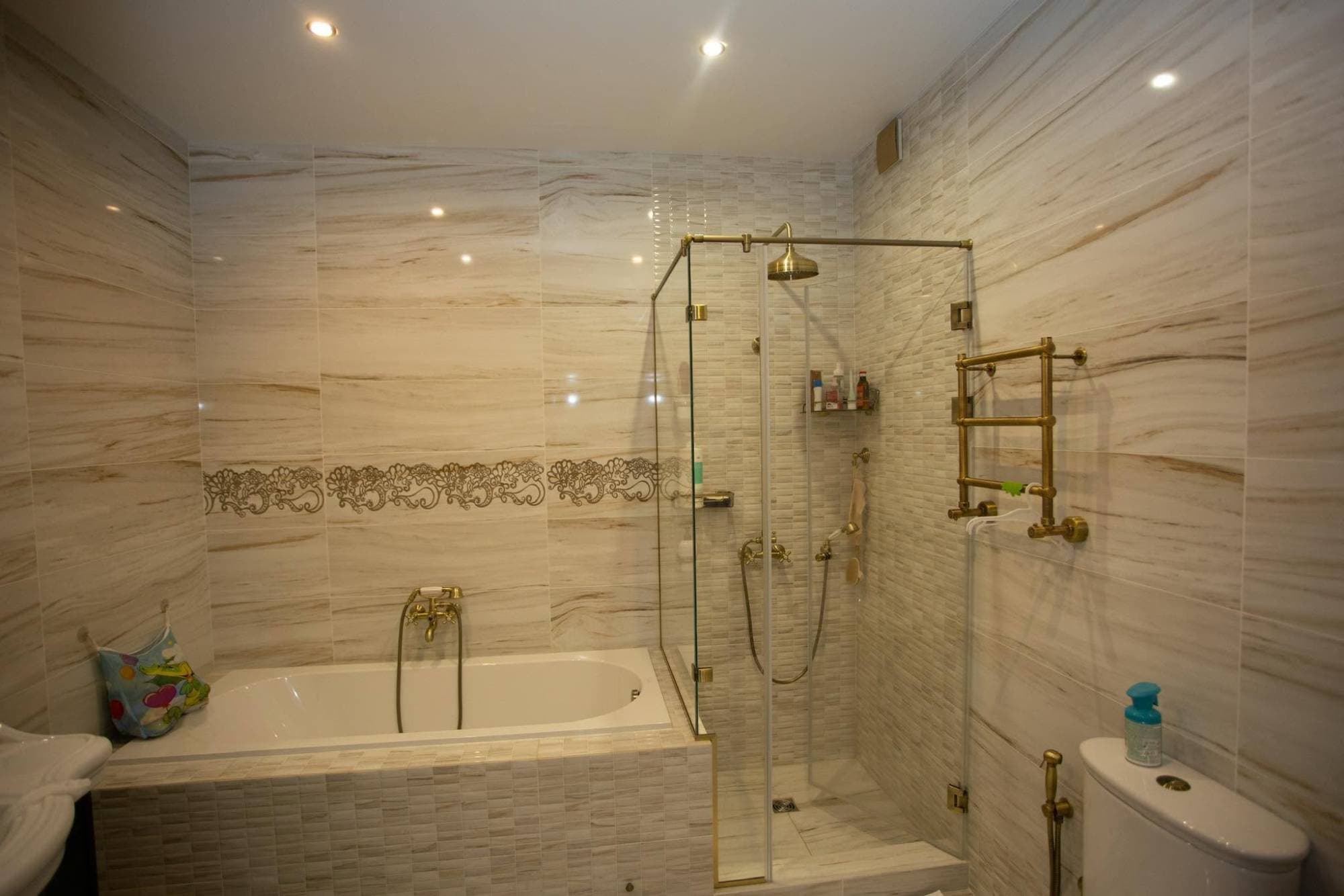 Bathroom with floor-to-ceiling marble-look wall tile and mosaic accents by I&I Home Repair