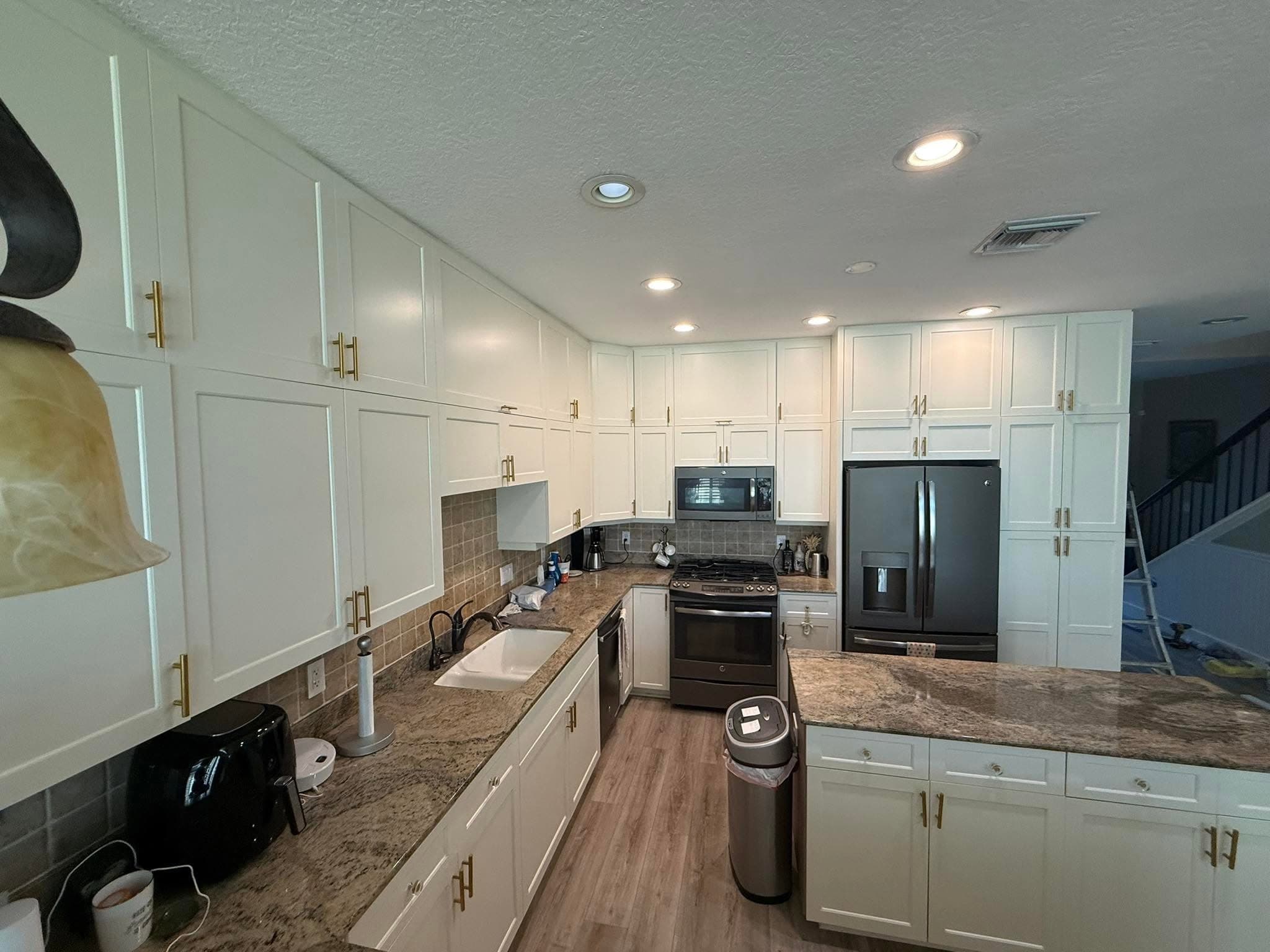 Kitchen with floor-to-ceiling white cabinets, gold hardware, and granite countertops by I&I Home Repair